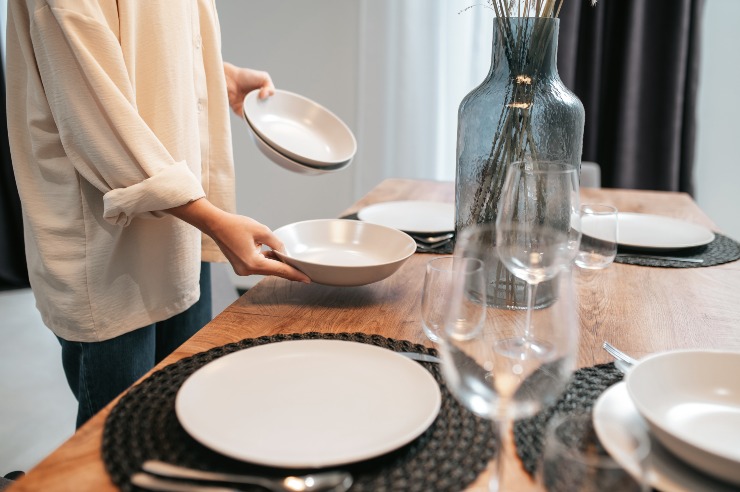 Una persona apparecchia la tavola con accessori di design