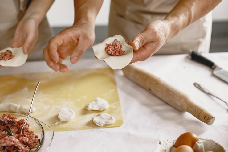 Due persone preparano a mano la pasta ripiena