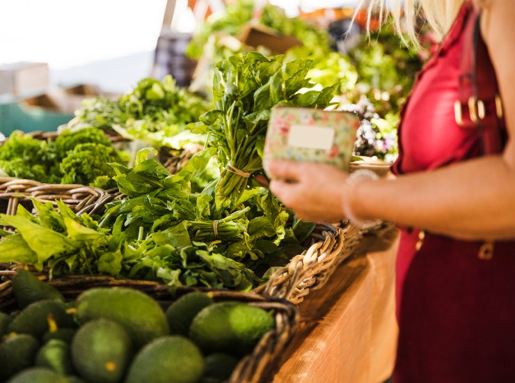 Una donna sceglie tra le verdure in vendita al supermercato