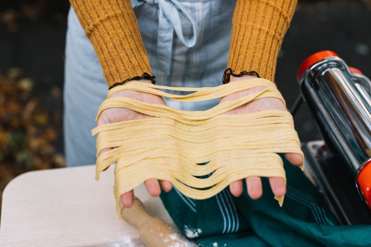 Una donna mostra della pasta tirata a mano