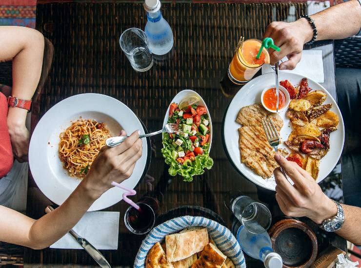 Due persone sedute a tavola che mangiano al ristorate