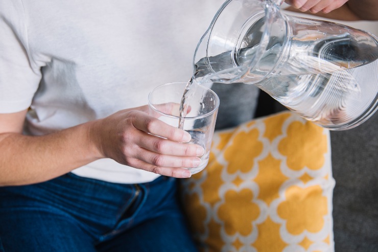 Una persona versa dell'acqua in un bicchiere