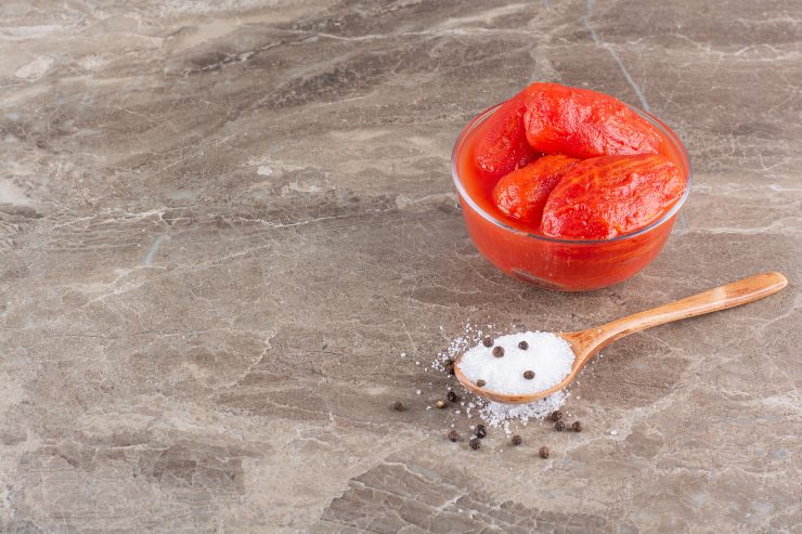Pomodori crudi vicino a un cucchiaio di sale