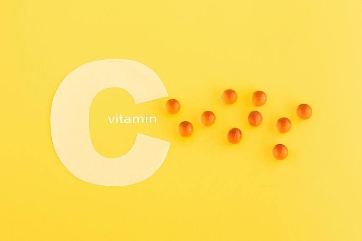 Concetto di Vitamina C con integratori su sfondo giallo