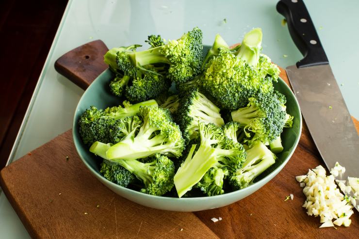 broccoli tagliati in ciotola su tagliere con coltello