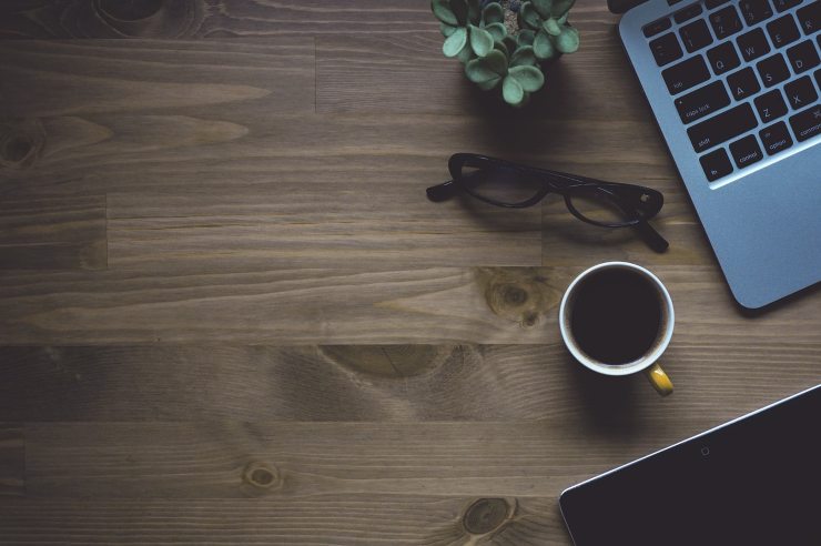 tazza di caffè su tavolo con occhiali e pc