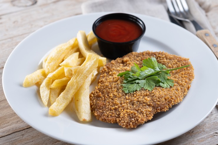 Cotoletta, patatine fritte e ketchup in un piatto