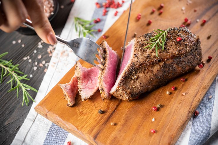 Una persona taglia a fette un filetto cotto alla perfezione