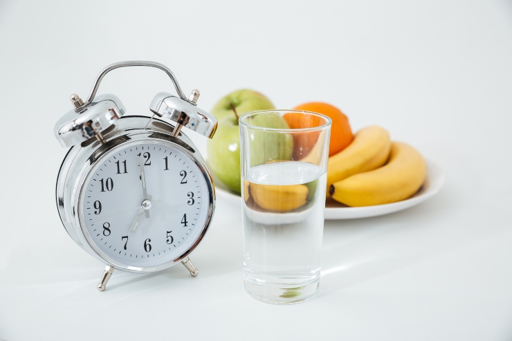 Un orologio vicino ad acqua e frutta