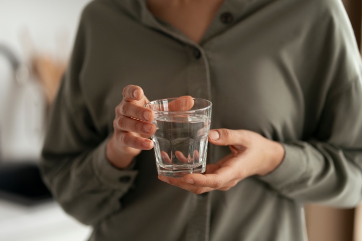 Una persona tiene in mano un bicchiere d'acqua