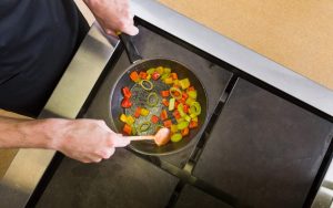 Una persona che cucina dei peperoni in padella