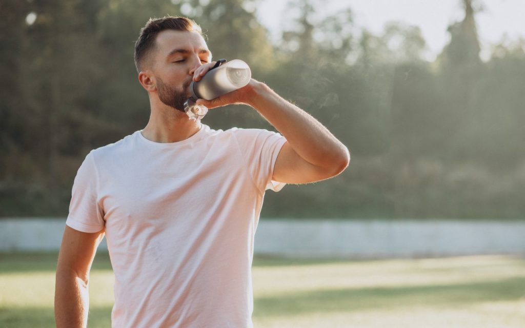 Un ragazzo all'aperto mentre beve da una borraccia
