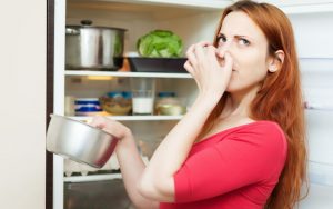 Una persona davanti a un frigorifero che emana cattivo odore