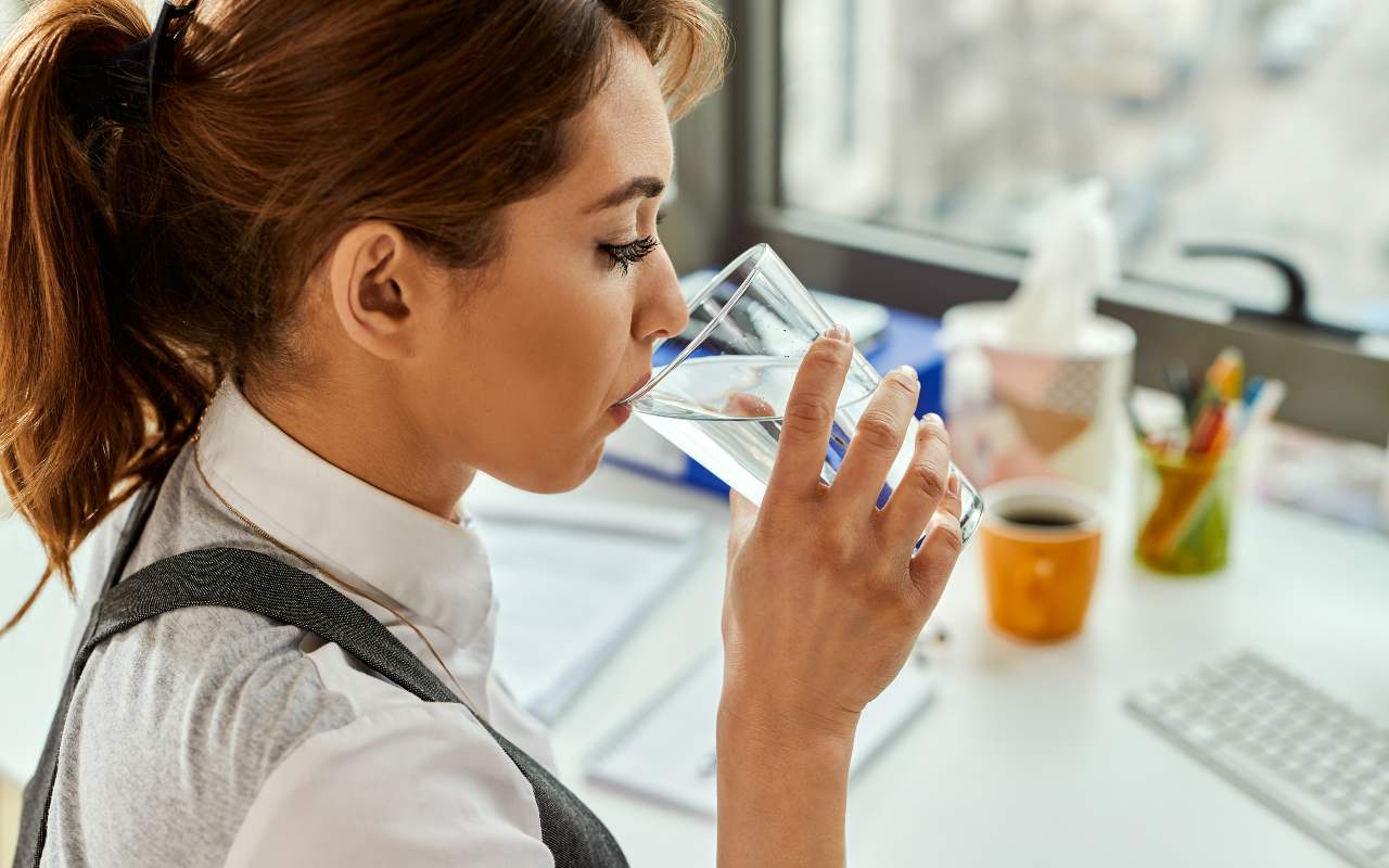 Una persona beve un bicchiere di acqua