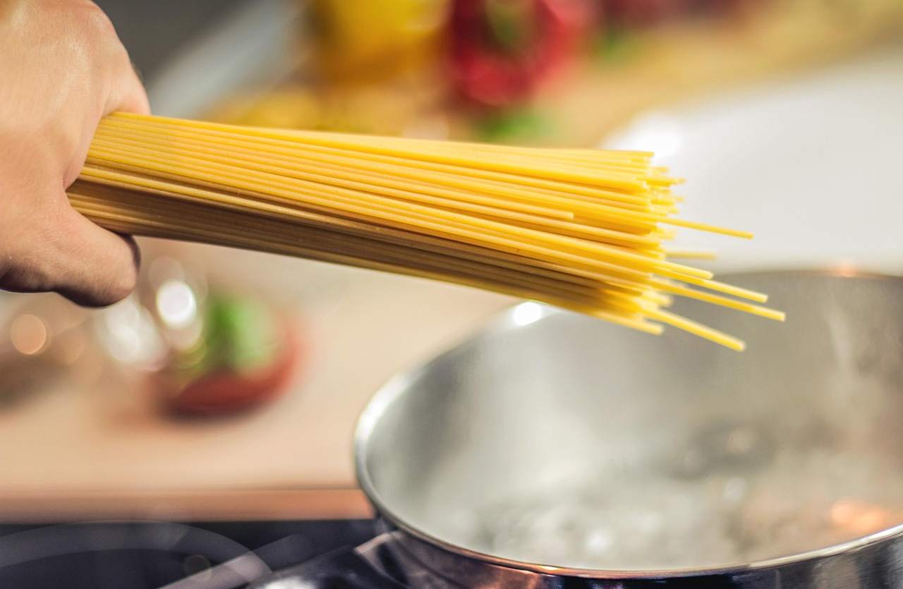 mano con spaghetti crudi