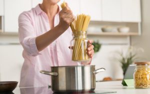 Una persona mette degli spaghetti in una pentola